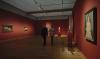 Ausstellungsaufnahme aus der Modigliani Ausstellung. Zwei Personen laufen an den Gemälden und einer Skulptur vorbei.